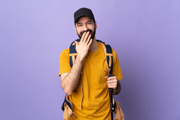 Caucasian handsome man with backpack and trekking poles over isolated background happy and smiling covering mouth with hand