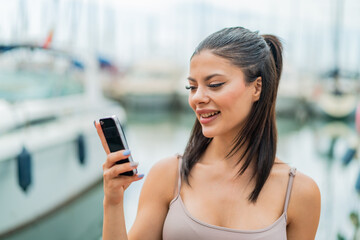 Young pretty woman using mobile phone at outdoors with happy expression