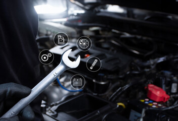 Car maintenance service concept , Mechanic hand holding a wrench for car repairing include an car engine blurred on background