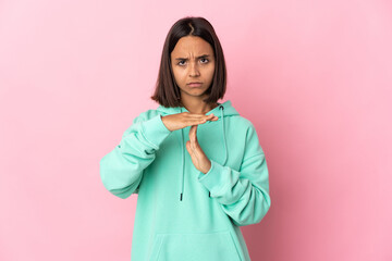Young latin woman isolated on pink background making time out gesture