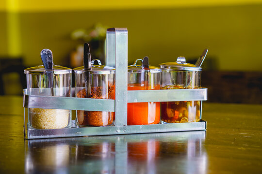 Condiment set of sugar, chilly flakes, chilli vinegar and fish sauce mixed chilli  in glass cruet on wooden table in resturant. For seasoning noodle.