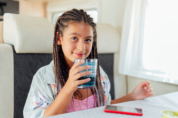 Caucasian cute girl with long hair is holding a water glass in her hands