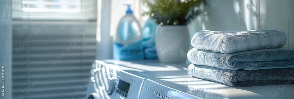 Poster a stack of clean, neatly folded laundry sits on top of a white washing machine. a window with blinds