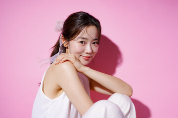 Naklejka premium ピンク背景で撮影をした若い女性のカジュアルなポートレート