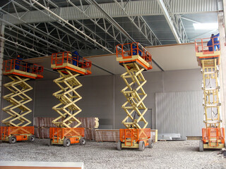 Workers installing PIR sandwich panels using scissor lifts inside a warehouse with a metal frame