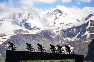 Lanslebourg-Mont-Cenis , France - June 20 2024: A group of cyclists tackle the steep Alpine climb in the back light.
