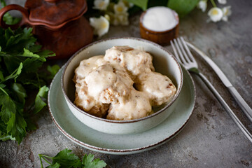 Meatballs in creamy sauce in a beautiful green plate on a gray background. Dinner for the whole family. Close-up