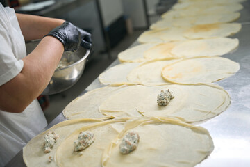 Obraz premium Woman puts fish filling on round pancakes