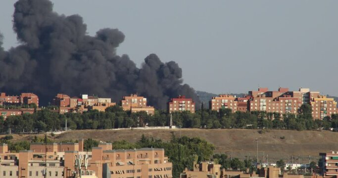 Large plume of dark, dense smoke from a fire behind buildings in the cityof Madrid, Spain
