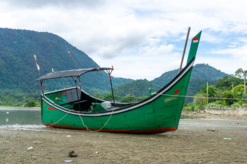 Traditional asian wooden longtail boat resting and standing at the seashore. Wooden boat at Ujung...