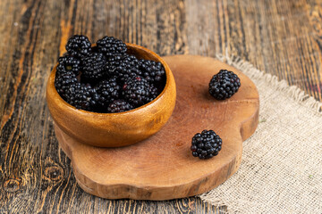 black ripe blackberries on the table in a wooden bowl