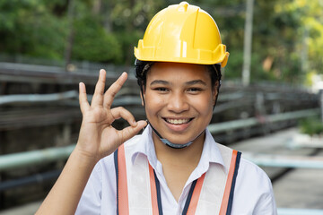 Successful happy smiling African woman industrial worker showing positive ok hand gesture for good, yes, acceptance, correct young female laborer wearing safety helmet and industrial site vest