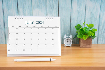 July Monthly desk calendar for 2024 year and alarm clock.
