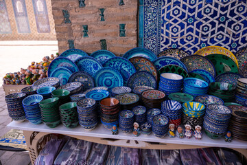 A table full of blue and green plates and bowls. The table is in front of a building
