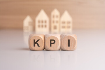 letters KPI on wooden blocks and house models on background, concept for Key Performance Indicators