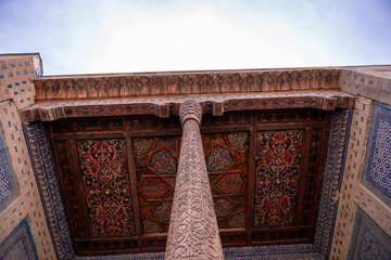 The ceiling of a building is decorated with a variety of colors and patterns. The design is intricate and detailed, giving the impression of a rich and ornate atmosphere. The combination of colors