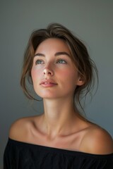 Fototapeta premium Young Woman Looking Upward in Black Off-the-Shoulder Top