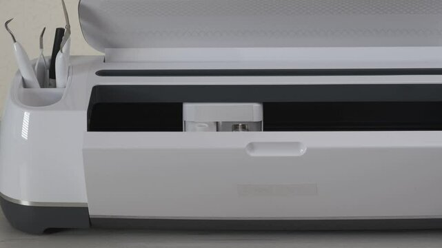 White Smart Cutting machine with gold door is ready for use at home. Plotter covers open, tools in storage cup. DIY paper craft, making gift from cardstock for family. Creative Hand crafting project. 