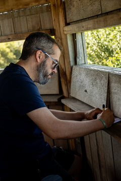 Man taking notes in a birdwatching hide at a nature reserve