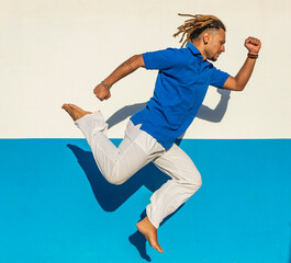Man with dreadlocks performing street dance on blue background