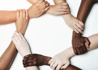 Hands, diversity and circle for synergy in studio with cooperation, commitment and teamwork with wrist grip. People, together and white background with support or solidarity, trust and collaboration