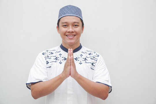 Asian Muslim man showing gesture of welcoming Ramadan and Eid Mubarak greeting isolated on white background. Religious people and Islamic lifestyle concept.
