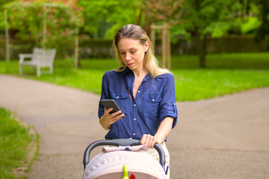 Mother Walking with Baby Stroller While Using Smartphone