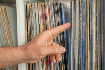 passionate elderly man, immersed in nostalgia, lovingly chooses disk, vinyl album on shelf, golden age music and connecting with past through cherished collection, Frankfurt - May 29, 2024
