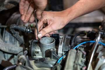 Obraz premium Car mechanic works on the engine of an old car