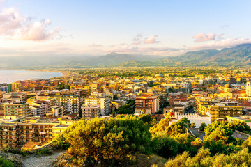 Fototapeta premium panoramic summer travel view from a hill to beautiful sea coast historical town with port, amazing ocean bay and gulf and beautiful mountains with scenic sunset on background.