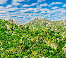 Obraz premium beautiful highland landscape of majectic green mountain with anciant buildings on top and slopes and scenic blue cloudy sky on background