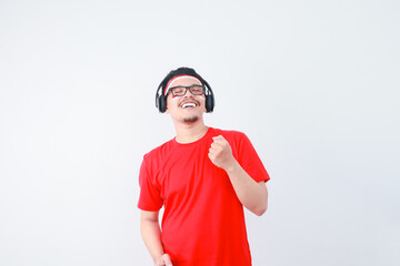 photo of a happy, attractive young Indonesian man wearing earphones, celebrating Indonesian independence