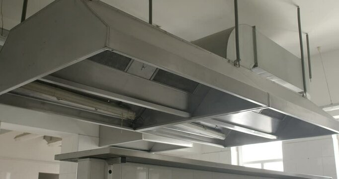 Interior details of a restaurant kitchen, sleek metallic extractor hood. Functional design elements of the kitchen. Cleanliness and professional culinary equipment. Restaurant infrastructure concept.