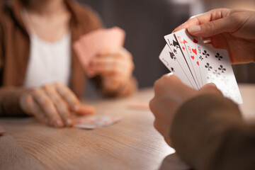 Two friends playing cards at home sitting at table, concept of leisure.