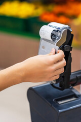 Close-up of a customer's hand using a credit card to pay a cashier at the checkout counter in a supermarket, cashless money and credit card payment technology concept.