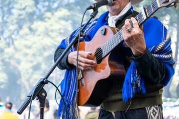 Gaucho argentino con poncho azul tocando la guitarra y cantando folklore