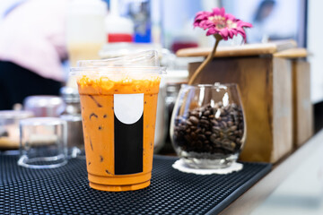 Iced Thai milk tea, Thai style cold drink in a plastic cup. On the table in the coffee shop