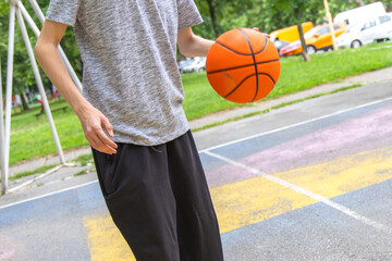 Fototapeta premium Young Man Dribbling Basketball On Outdoor Court During The Day
