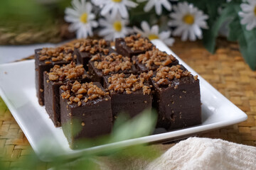 Kuih kole kacang, a steamed Malaysian cake, made with fried green bean flour, coconut milk, and palm sugar.  The decoration of the cake is from coconut oil grease or residue. Selective focus.