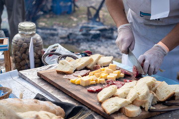 Deliciosa picada de fiambres, pan y quesos siendo preparada al aire libre