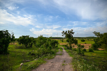 road in the countryside with wind farm in the background, Clean and smart energy exploitation, contributing to local economic development