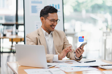 Smiling businessman professional using smartphone for email with notification alert while working...