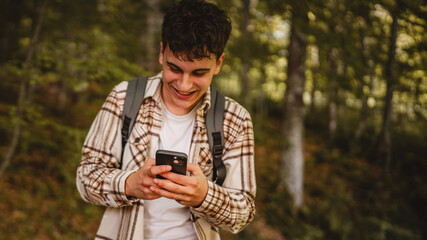 young man walk around forest and use cellphone for directions
