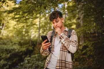 young man walk around forest and use cellphone for directions