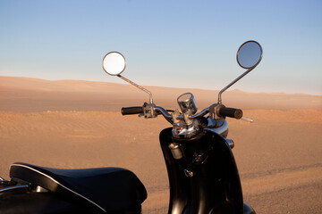 The Retro black scooter at sunset in the golden sand of the Namib Desert