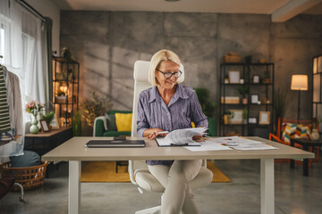 Mature woman work from home and sign insurance,document on clipboard