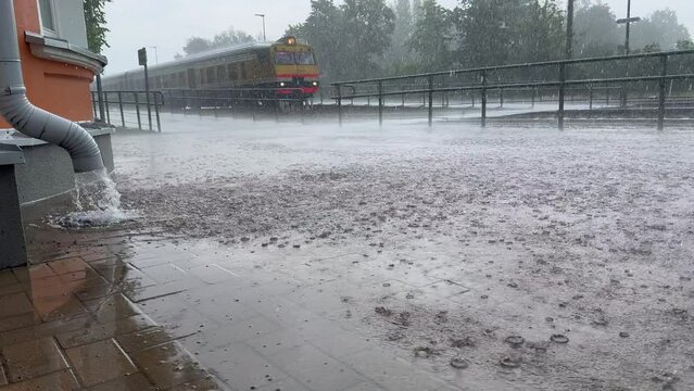 Gutter  by the wall of the building and train in the background, rapid flow of water after heavy rain.