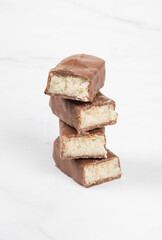 Vegan dessert. Candy bar with coconut pulp, in chocolate. White background. Close-up
