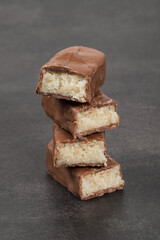 Candy bar with coconut pulp, in chocolate. Dark gray background. Close-up