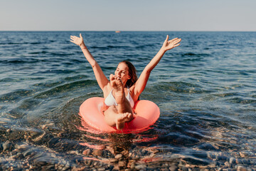 A woman is in the ocean on a red inflatable raft